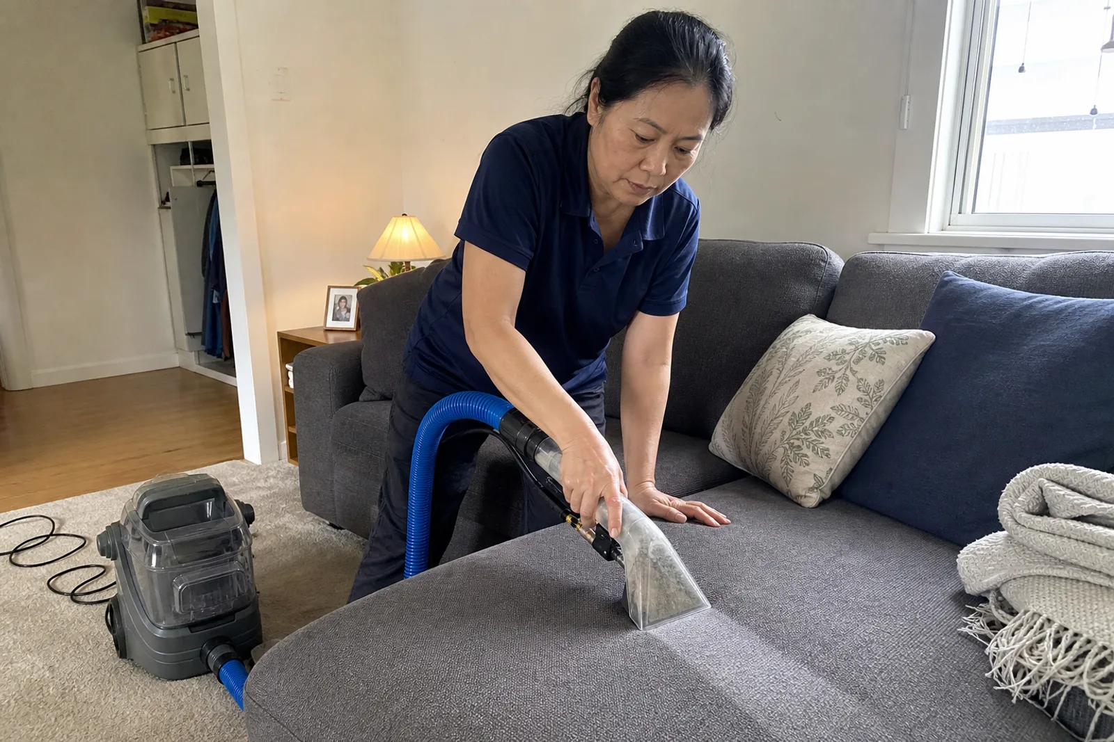 Technician cleaning a fabric sofa cushion with a small extraction tool